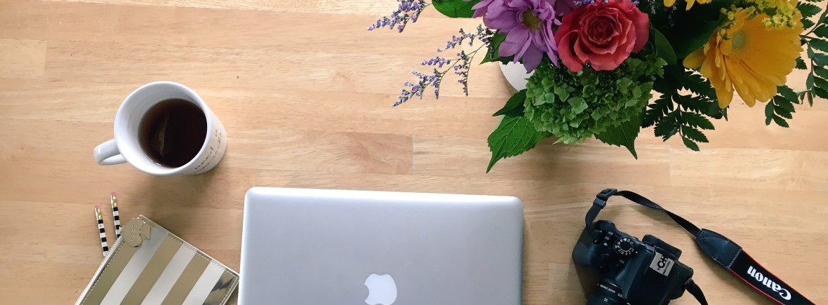 workspace - tea, pencil case, laptop, camera, flowers